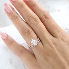 a woman's hand with a diamond ring on top of her finger and pink manicured nails