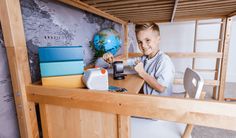 a young boy sitting on top of a bunk bed next to a desk and chair