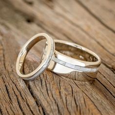 two wedding rings sitting on top of a wooden table