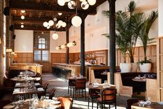 an empty restaurant with tables and chairs in front of the bar area, surrounded by potted palm trees