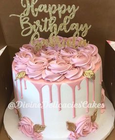 a birthday cake decorated with pink icing and gold glitters is in a box