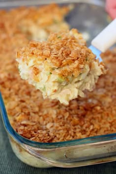 a spoonful of chicken casserole is being lifted from the casserole dish