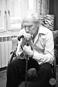 an old man sitting in a chair holding a cane