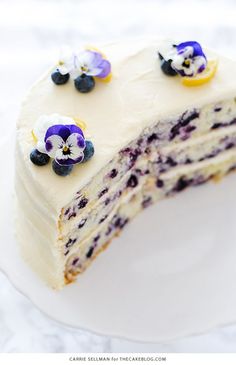 a piece of cake with white frosting and blueberries on top