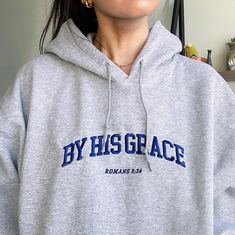 "By His Grace, Romans 3:24" embroidered on a comfy hoodie. Minimal Christian apparel, a great gift for both men and women. Everyone needs a cozy go-to hoodie to curl up in, so go for one that's soft, smooth, and stylish.  * 50% pre-shrunk cotton, 50% polyester * Fabric weight: 8.0 oz/yd² (271.25 g/m²) * Air-jet spun yarn with a soft feel and reduced pilling * Double-lined hood with matching drawcord * Quarter-turned body to avoid crease down the middle * 1 × 1 athletic rib-knit cuffs and waistba Christian Gym, Church Merch, Holy Girl, By His Grace, Romans 3, Aesthetic Christian, Gym Apparel, Christian Hoodies, College Fits