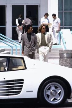 two men walking past a white sports car