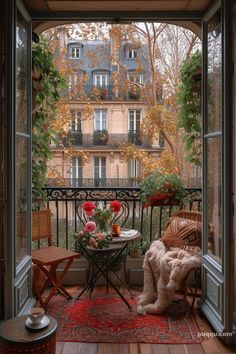 an open door leading to a balcony with furniture and flowers on the table in front of it