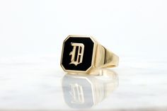 "This is an impressive D letter signet ring. It is made of 14k, and a black enamel bed upon which the gold letter luxuriously and boldly shines! Get this elegant gold initial signet ring for your loved one, or yourself, to upgrade every outfit you own with a meaningful, timeless, bold and impressive piece of jewelry. ✿ Item details ✿ ✿ Ring Size: 8 1/4 US, 0.722\" Diameter ✿ Materials: - 14k Yellow Gold  - Black enamel ✿ Measurements: - Front width: 14 mm (0.55\")  - Back width: - 4 mm (0.16\") Black 14k Gold Engraved Signet Ring, Black Engraved 14k Gold Ring, Black 14k Gold Hallmarked Engraved Ring, Black 14k Gold Engraved Ring, Luxury 14k Gold Enamel Ring Gift, Luxury 14k Gold Enamel Ring As Gift, Luxury Polished Enamel Ring In 14k Gold, Timeless Gold Signet Ring With Black Enamel, Yellow Gold Signet Ring With Black Enamel For Gift