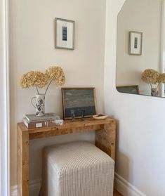 a wooden table with a mirror and vase on top of it next to a stool