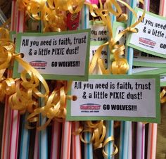 some cards with ribbons and sayings attached to them are hanging on the wall in front of colorful striped straws