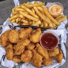 fried chicken and french fries with ketchup are on a plate next to a bowl of dipping sauce