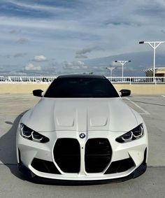 the front end of a white car parked in a parking lot