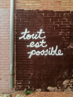 graffiti on the side of a brick building reads, tout est possle