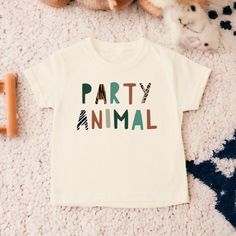 a baby t - shirt with the words party animal printed on it next to stuffed animals