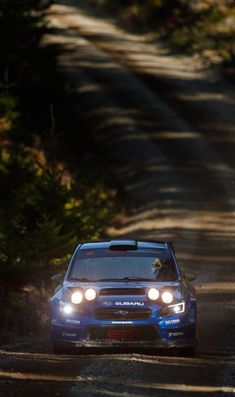 a blue car driving down a dirt road