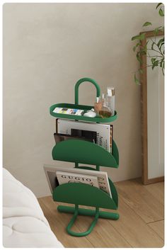 a stack of books and magazines sitting on top of a green shelf next to a plant