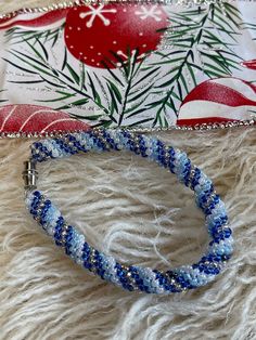 two bracelets sitting on top of a white fur covered floor next to a christmas ornament