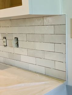 a kitchen counter with some white tiles on the wall and one light switch in the middle