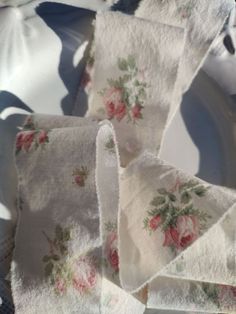 several pieces of cloth with roses on them sitting on a white tablecloth covered plate