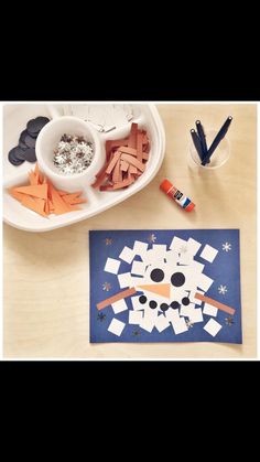 a paper snowman is on the table next to crayons and glues