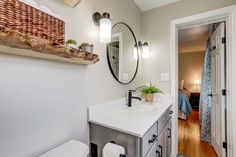 Master bathroom remodel includes glass shower doors with matte-black grids, enclosing an all-tile shower that features a bench seat and Caribbean-blue tiled niche, swarm gray vanity with white marble top, distressed vinyl plank floor, and floating live-edge wood shelving