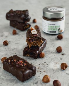 three pieces of chocolate and nuts on a table next to a jar of nut butter