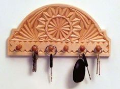 a wooden key holder with several keys hanging from it's hooks on a wall