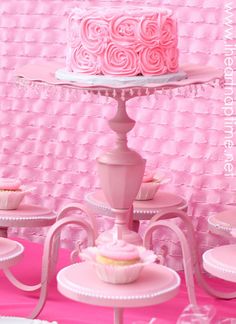 there is a pink cake and cupcakes on the table