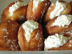 a bunch of doughnuts in a box with cream on them and sprinkled