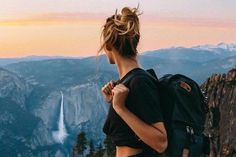 a woman standing on top of a mountain with a backpack