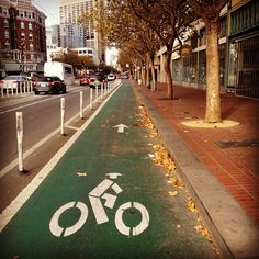 a bike lane on the side of a street with trees and buildings in the background