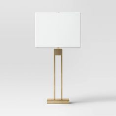 a lamp with a white square shade on the base and a gold frame around it