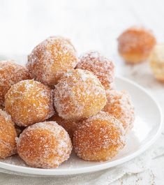 powdered sugar coated donuts on a white plate