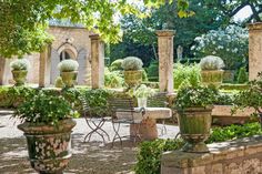 an outdoor dining area with tables and chairs in the middle of it, surrounded by greenery