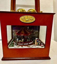 a small wooden clock with a carousel in the center and christmas decorations on it's sides