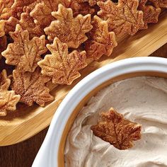 a bowl of whipped cream next to some leaf shaped cookies