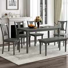 a dining room table with chairs and a vase filled with fruit on top of it