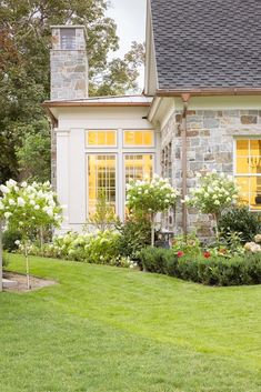 a house that has some flowers in front of it and grass on the ground outside