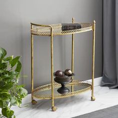 a gold metal shelf with two bowls on it and a potted plant next to it