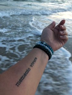 a person with a wrist tattoo that says, the ocean waves are crashing in front of them