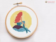 the cross stitch pattern is being displayed in front of an embroidery hoop with scissors and thread