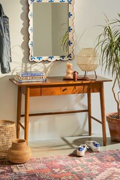 a wooden table topped with a mirror next to a potted plant and a rug