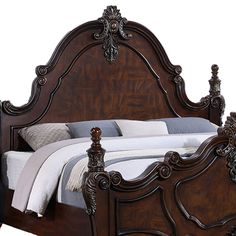 an ornate wooden bed frame with white sheets