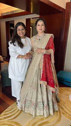 two women standing next to each other in front of a bed wearing white and red outfits