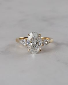 an oval cut engagement ring with three pear shaped diamonds