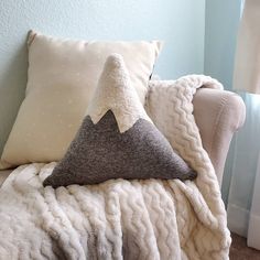 a white chair with two pillows on it and a blanket draped over the back of it