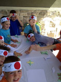 a group of children sitting at a table with paper hats on their heads and hands