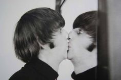 two young men kissing each other in front of a black and white photo on the wall