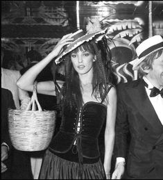 black and white photograph of woman in dress carrying basket with man standing next to her