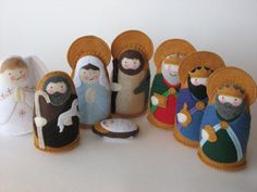 several felt nativity figurines are displayed on a white surface with one holding a baby jesus